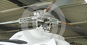 Circular detail footage of helicopter rotor. Strong mast, rotor hub and three blades against hangar ceiling. Airport and