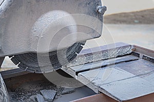 The circular diamond saw cuts granite sidewalk tiles. Concrete cutting machine close-up