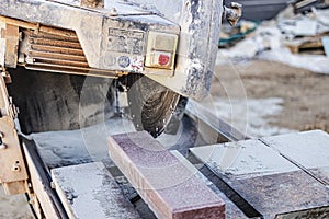 The circular diamond saw cuts granite sidewalk tiles. Concrete cutting machine close-up