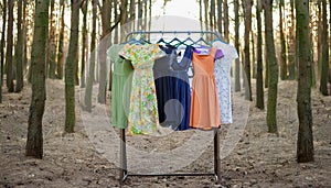 Circular economy. Offbeat image. Clothes hanger with dresses in the forest. Concept for organic clothes, eco-friendly, ecological photo