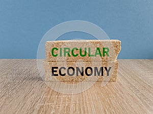 Circular economy symbol. Concept green words Circular economy on brick blocks. Beautiful wooden table blue background. Business