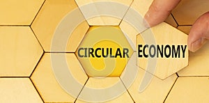 Circular economy symbol. Concept words Circular economy on beautiful wooden puzzles. Beautiful yellow background. Businessman hand