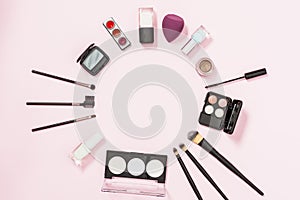 circular frame made with makeup brushes nail polish bottle eyeshadow blender pink background. High quality photo