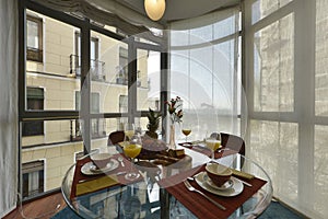 Circular glass dining table with fresh fruit and orange juice with a large glass bay window