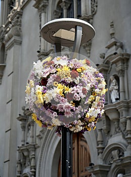 Circular Hanging Basket of multi-colored flowers underneath a streetlamp.