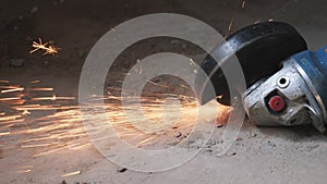 Circular metal saw cutting a metal part in concrete floor generation orange sparks. Worker cuts metal with orange sparks flying