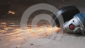 Circular metal saw cutting a metal part in concrete floor generation orange sparks. worker cuts metal with orange sparks flying. s