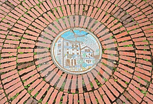 A circular of old red brick floor pattern background texture with mosaic picture in the middle