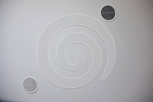 Circular plastic air vent in white wall