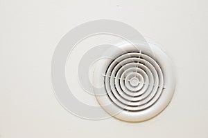 Circular plastic air vent in white wall