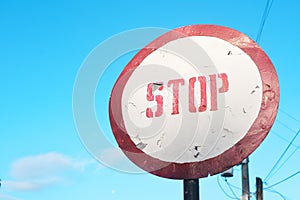 Circular red stop sign road warning against clear blue sky.