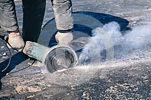 Circular saw cutting reinforced concrete slab during roof repair. Worker hands with with electric angle grinder closeup.