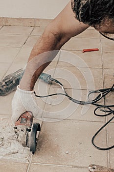 A circular saw. A man sawing ceramic tiles. Worker sawing a tile on a circular saw. Construction works. Selective focus