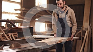 The circular saw in process. The carpenter cuts the edges of a large piece of wood . Carpenter`s workshop