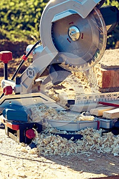 Circular saw stands in sawdust strewn after sawing wooden carved platbands