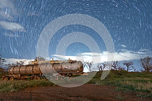 Circular star trails with the north star above abandoned machines in a Field