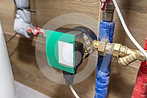 Circulation pump for hot water in a modern gas boiler room lined with ceramic tiles.