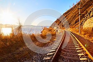 Circum Baikal railway running along the shore of Lake Baikal on an autumn sunny day with a yellow landscape around