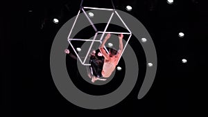 Circus aerial cube duo on black background performing tricks. Man and women fly on stage