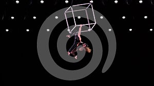 Circus aerial cube duo on black background performing tricks. Man and women fly on stage