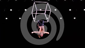 Circus aerial cube duo on black background performing tricks. Man and women fly on stage