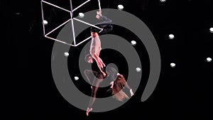 Circus aerial cube duo with on black stage background performing trick, highly risky drop. Concept of trust and