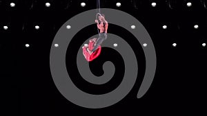 Circus aerial hoop duo on black background performing beautiful tricks. Man and women fly on stage