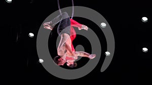 Circus aerial hoop duo on black background performing beautiful tricks. Man and women fly on stage