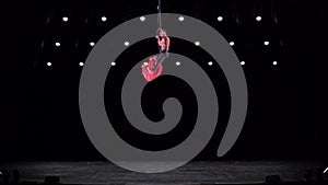 Circus aerial hoop duo with on black stage background performing trick, highly risky drop. Concept of trust and