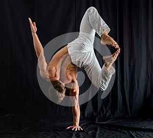 circus artist keeps balance on one hand isolated on a black background. Concept of individuality, creativity and self