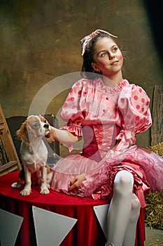 Circus trainer. Portrait of little cute beautiful girl in festive dress training funny doggy at vintage circus. Holidays