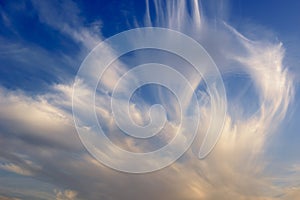 Cirrostratus clouds in blue sky with light orange color from evening sun photo