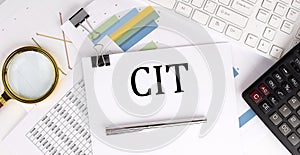CIT text on the white paper on the light background with charts paper ,keyboard and calculator photo