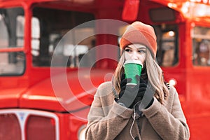 Citar dama en cálido pelo naranja un sombrero de pie en calles en de el autobús bebiendo café taza 