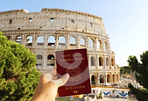 Citizenship concept: hand hold Italian passport in front of Colosseum in Rome