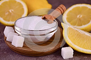 Citric acid in a bowl and fresh lemons.Close-up.