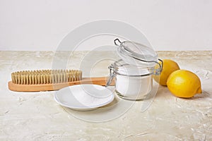 Citric acid, soda, lemons and a wooden brush on a light background for eco cleaning, natural and non-toxic detergents, zero waste