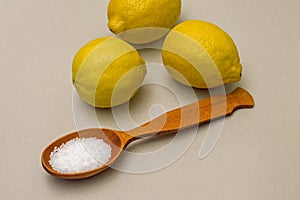 Citric acid in spoon on background of lemons