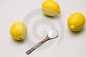 Citric acid in wooden spoon and fresh lemons