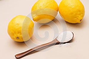 Citric acid in a wooden spoon and lemons