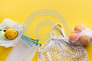 Citrics in reusable eco-friendly mesh bags with on yellow background. Zero waste concept. Ecological shopping. Stop pollution