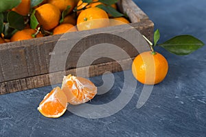 Citrus. Bright ripe tangerines with green leaves in a wooden bo
