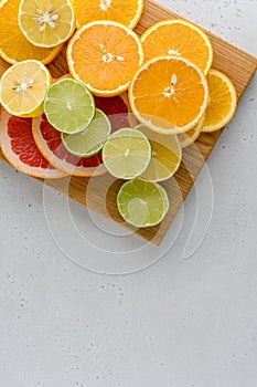 Citrus composition on cutting board. Many halved lemons, limes, grapefruits. Vertical, copy space