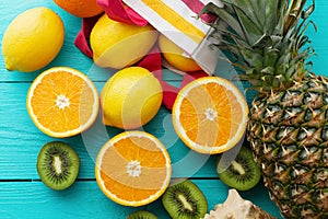 Citrus fresh food. Summer holidays. Orange, kiwi, pineapple, lemon and sea shell on blue wooden background. Vacation