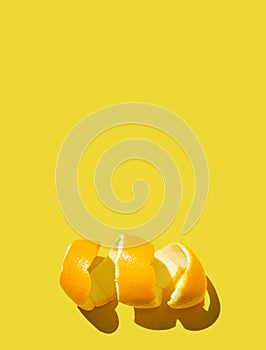 Citrus fruit concept with fresh orange peel spiral on a bright yellow background. Minimal style flat lay with room for text