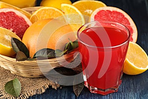 Citrus fruit. Various citrus fruits with leaves of lemon, orange, grapefruit in a basket and grapefruit juice on a blue wooden tab