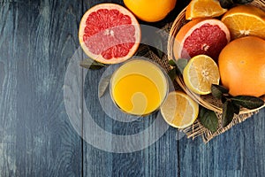 Citrus fruit. various citrus fruits with leaves of lemon, orange, grapefruit in a basket and orange juice on a blue wooden table.