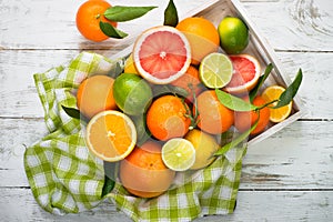 Citrus fruit in wooden tray on white table.