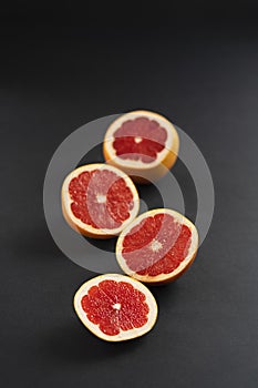 Citrus fruits cut into slices on a black background, minimalism