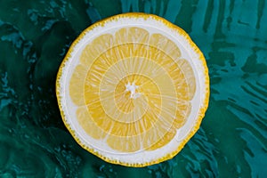 Citrus fruits in green water background with concentric circles and ripples. Refreshing summer concept